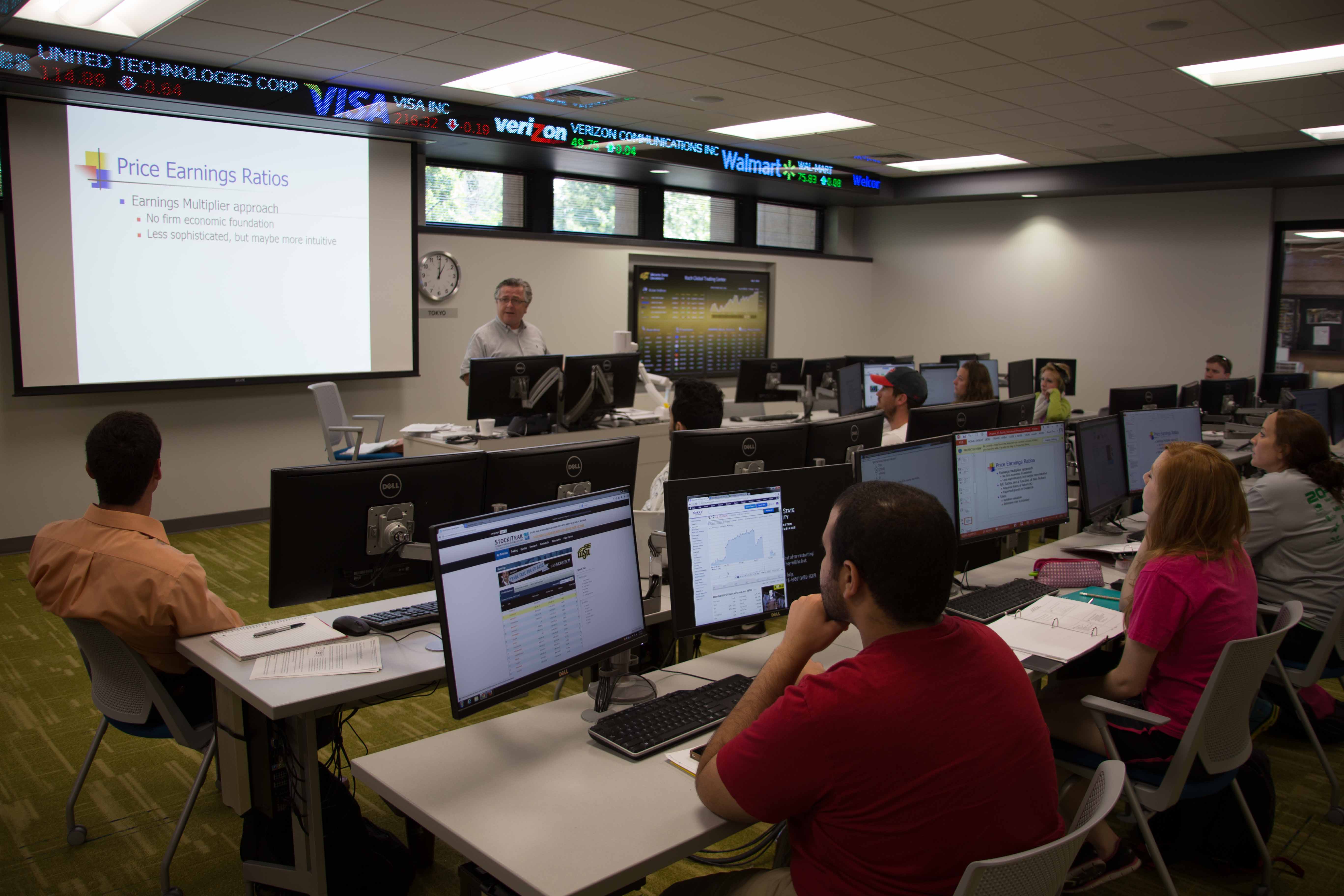 A group of students in a classroom watching a presentation on Price Earnings Ratios.