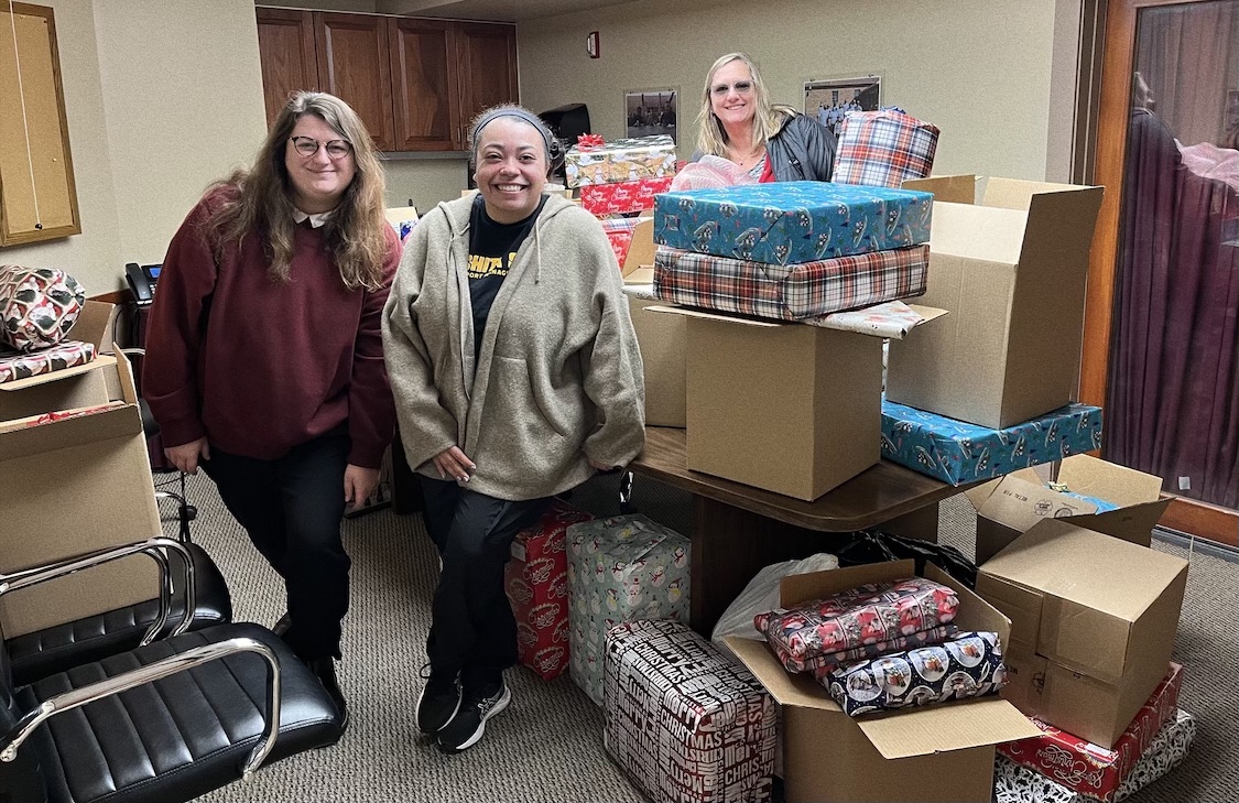 Rosie Marino, CAS Administrative Specialist; Heidi Cornell, CAS Associate Dean & Accreditation Officer; and Amaya Harris, CAS graduate student assistant pose with wrapped gifts for the Starkey Inc. Angel Tree Project