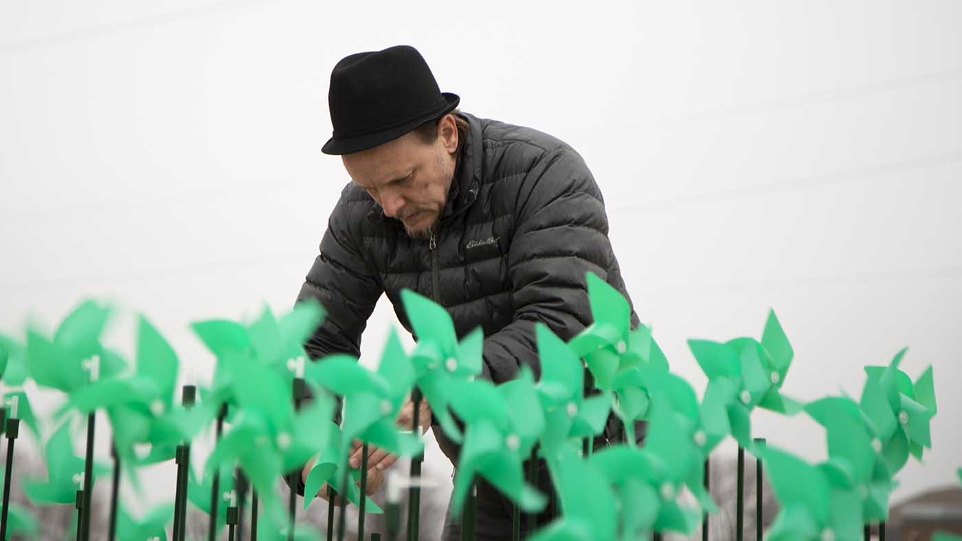 Photo of Levente Sulyok repairing a sculpture made from a series of pinwheels.
