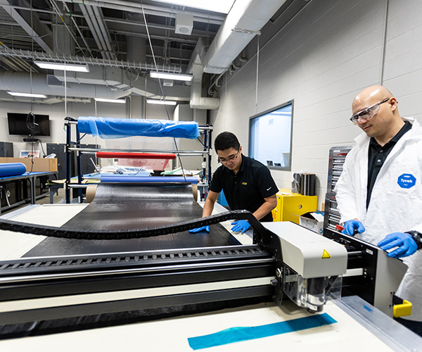 Two NIAR employees working with composite materials on a table in the composites laboratory at NCAT.